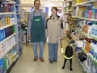 Winkelen met de blindengeleidehond, met hulp van een winkelbegeleider / Bron: Kim Bols, http://www.visuelehandicap.be